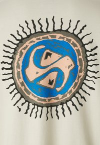 Light-colored cotton t-shirt with a large circular graphic. Features blue and pink swirling patterns with black sunray accents surrounding it.