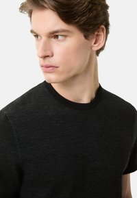 Sort T-shirt med rund hals og tekstureret finish samt kontrasterende sort krave. Har en afslappet pasform og korte ærmer.