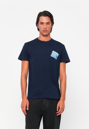 Marineblå bomulds T-shirt med korte ærmer, prydet med et rektangulært blåt grafisk motiv på venstre brystområde. Klassisk rund halsudskæring.
