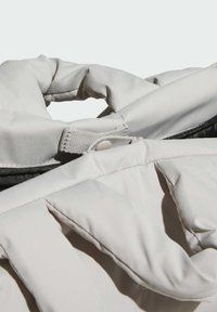 Light gray, padded fabric bag with a twisted handle; features a button and strap closure with a contrasting black interior.