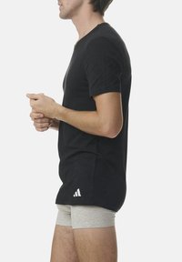 Black short-sleeve t-shirt with round neckline, made of soft fabric, features a white Adidas logo on the lower left side.