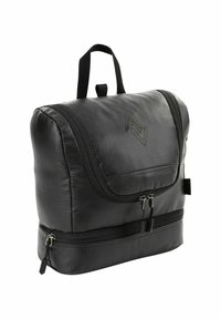 Sac en nylon noir avec une fermeture à rabat, logo bien en évidence, bandoulière réglable et double compartiment zippé en bas. Fini texturé.