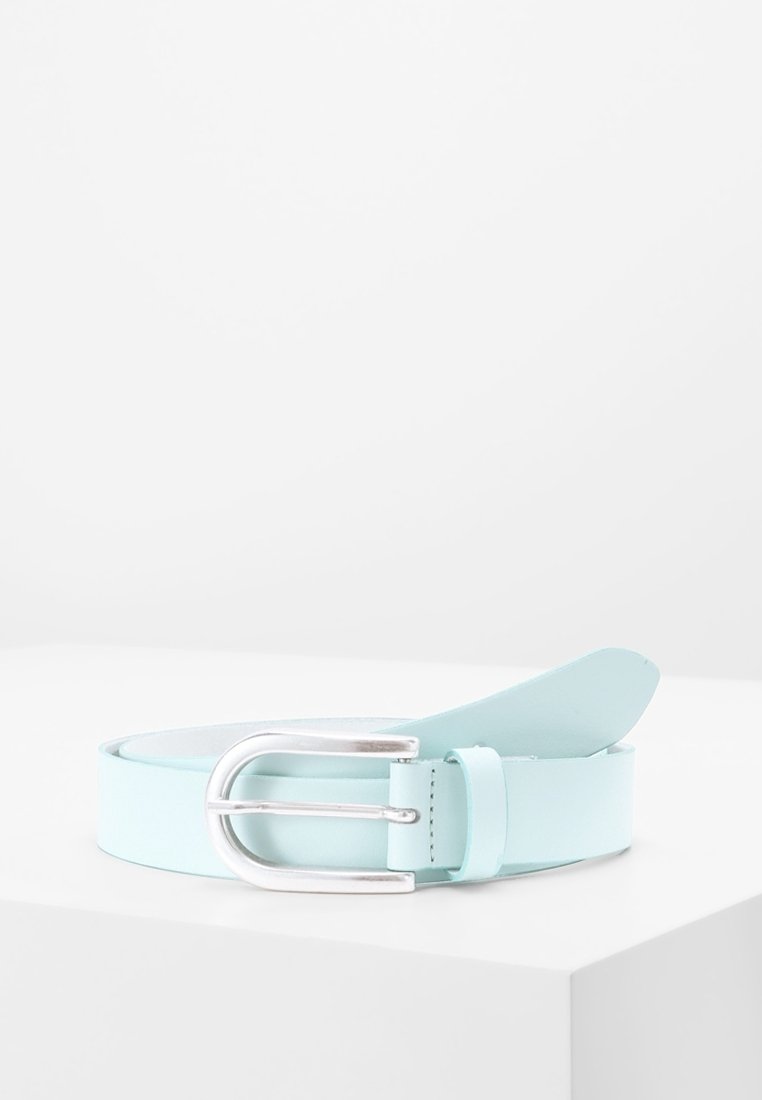 Ceinture en cuir bleu clair avec une boucle métallique argentée, enroulée et placée sur une surface blanche sur un fond gris clair uni.