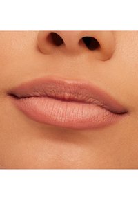 Nærbilde av myke, glatte lepper i en naken rosa nyanse med subtil tekstur og naturlig form, rammet inn av en nøytral hudtoned bakgrunn.