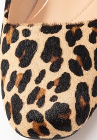 Ballerines en imprimé léopard, fabriquées dans un matériau en fausse fourrure doux et texturé, avec des taches brunes et noires sur un fond beige. Design à bout rond.