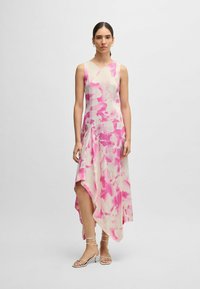 Ärmelloses Kleid in Beige mit pinkem abstraktem Blumenmuster. Asymmetrischer Saum, leichtes Material und lässige Passform. Flache Riemchensandalen.