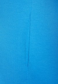 Jasnoniebieska tkanina o gładkiej teksturze z pionowym szwem biegnącym wzdłuż długości, prezentująca czyste wykończenie i jednorodny kolor.