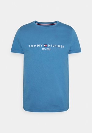 Blaues kurzärmeliges T-Shirt mit Rundhalsausschnitt und weißem "Tommy Hilfiger EST. 1985"-Text sowie kleinem rot-weiß-blauen Flaggenlogo auf der Brust.