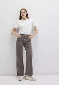 Wide-leg corduroy trousers in grey, featuring a high waist and front pockets, paired with a plain white t-shirt and casual sneakers.