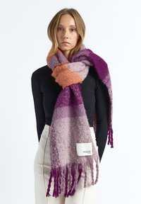 Multicolor wool scarf featuring shades of purple, orange, and lavender with fringed ends and a white fabric tag with "maze" branding.