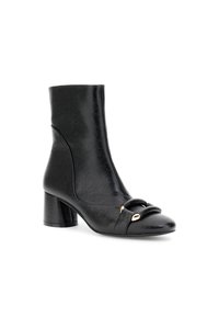 Stivaletto in pelle nera con punta rotonda, tacco spesso, cinturino decorativo con dettagli dorati e una superficie liscia e leggermente testurizzata.