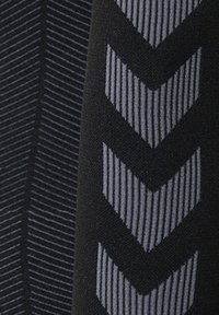 Primer plano de tela negra con patrones de chevrones verticales en rayas gris y gris oscuro.