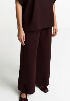Burgundy oversized top and wide-leg pants made of soft fabric, featuring a loose fit and a smooth texture. Paired with matching burgundy shoes.