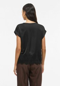 Mustast satiinist topp lühikeste keeratud varrukatega ja pitsist äärisega ääres. Tagaküljel on sile tekstuur ja lõõgastav istuvus.