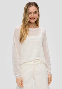 Top lungo bianco leggero a maniche lunghe con una texture leggermente trasparente e un motivo a righe orizzontali; scollatura rotonda e vestibilità rilassata.