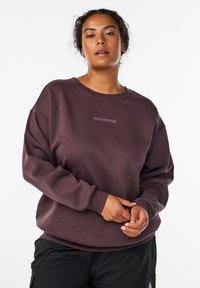 Maroon sweatshirt with a crew neckline and ribbed cuffs. Features "MILESTONE" embroidered in a lighter shade. Soft, textured fabric.