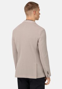 Ljust beige texturerad kavaj med slagkrage, enkel ryggslits och knäppte manschetter. Skräddarsydd passform med en slät yta.