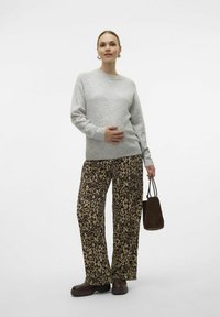Svjetlosiva dukserica, labave hlače s leopard-printom, smeđe platforme i mala smeđa torba. Glatke teksture s odvažnim uzorcima.