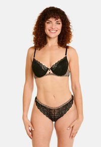 Soutien-gorge en dentelle noire et culotte assortie avec des accents en imprimé léopard. Présente des bords festonnés, un soutien-gorge à armatures et des bretelles réglables.