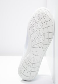 Witte sneakerzool met een geribbelde rubberen oppervlakte voorzien van een geometrisch patroon en een logo. Minimalistisch ontwerp met ronde randen.