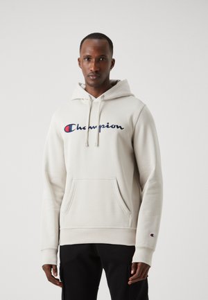 Sudadera color beige claro hecha de algodón, con un bolsillo frontal, capucha con cordones y logotipo bordado de "Champion" en azul marino, con puños acanalados.