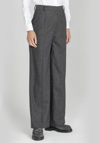 Szare, szerokie spodnie wykonane z teksturowanej tkaniny. Posiadają wysoki stan i subtelne zakładki. Stylizowane z białą koszulą i szarymi butami.