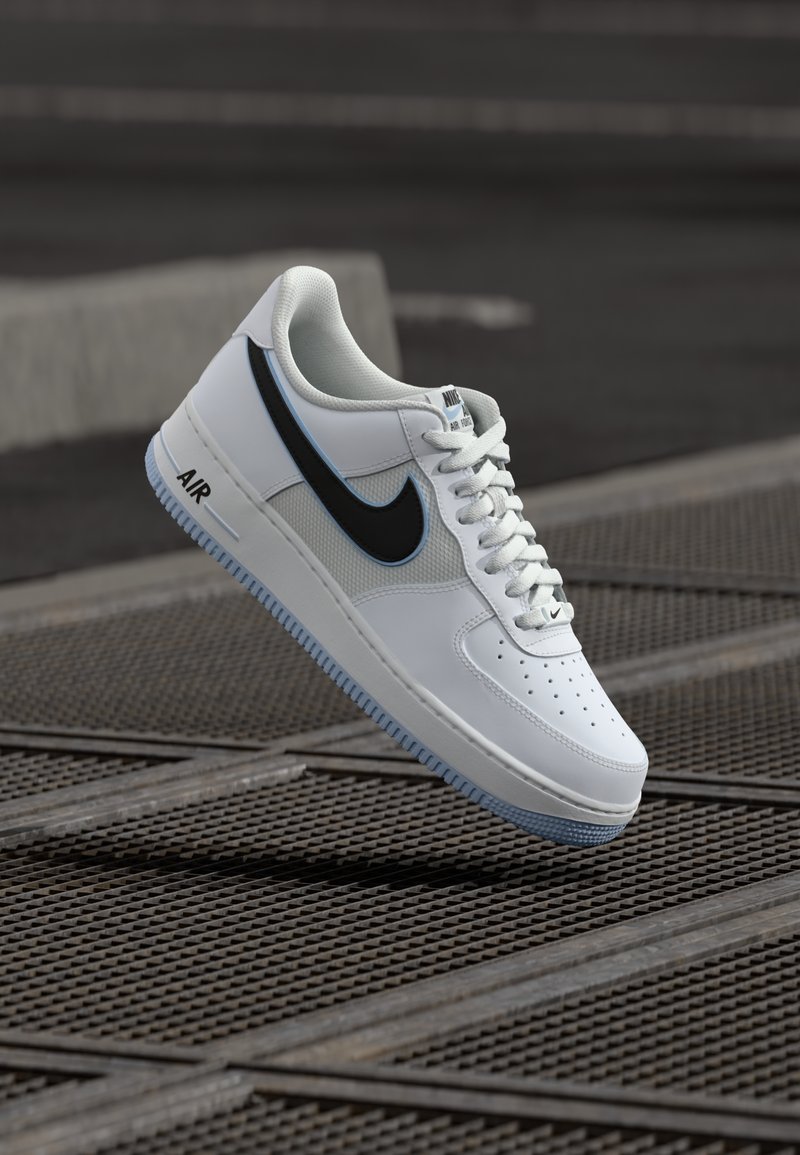 Weiße Nike Air Force 1 Sneaker mit einem schwarzen Swoosh, Mesh-Akzenten und einer hellblauen Sohle. Verfügt über eine perforierte Zehenpartie zur Belüftung.