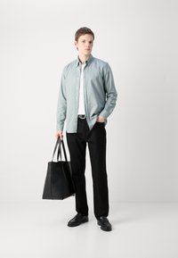 Lichtblauw overhemdd shirt, wit t-shirt, zwarte broek, zwarte leren tote bag, en zwarte schoenen. Eenvoudig ontwerp met een comfortabele pasvorm.