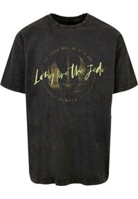 Camiseta negra de algodón con cuello redondo y mangas cortas, con el texto impreso "Que viva el Jedi" en verde claro y un diseño circular.