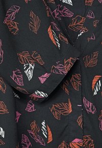 Svart tyg med ett bladmönster i rosa, orange och vitt. Urringningen har en vikkrage och knapppdetalj.