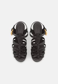 Black high-heeled sandals with a strappy design, featuring horizontal and vertical straps, a buckle accent, and a smooth texture.