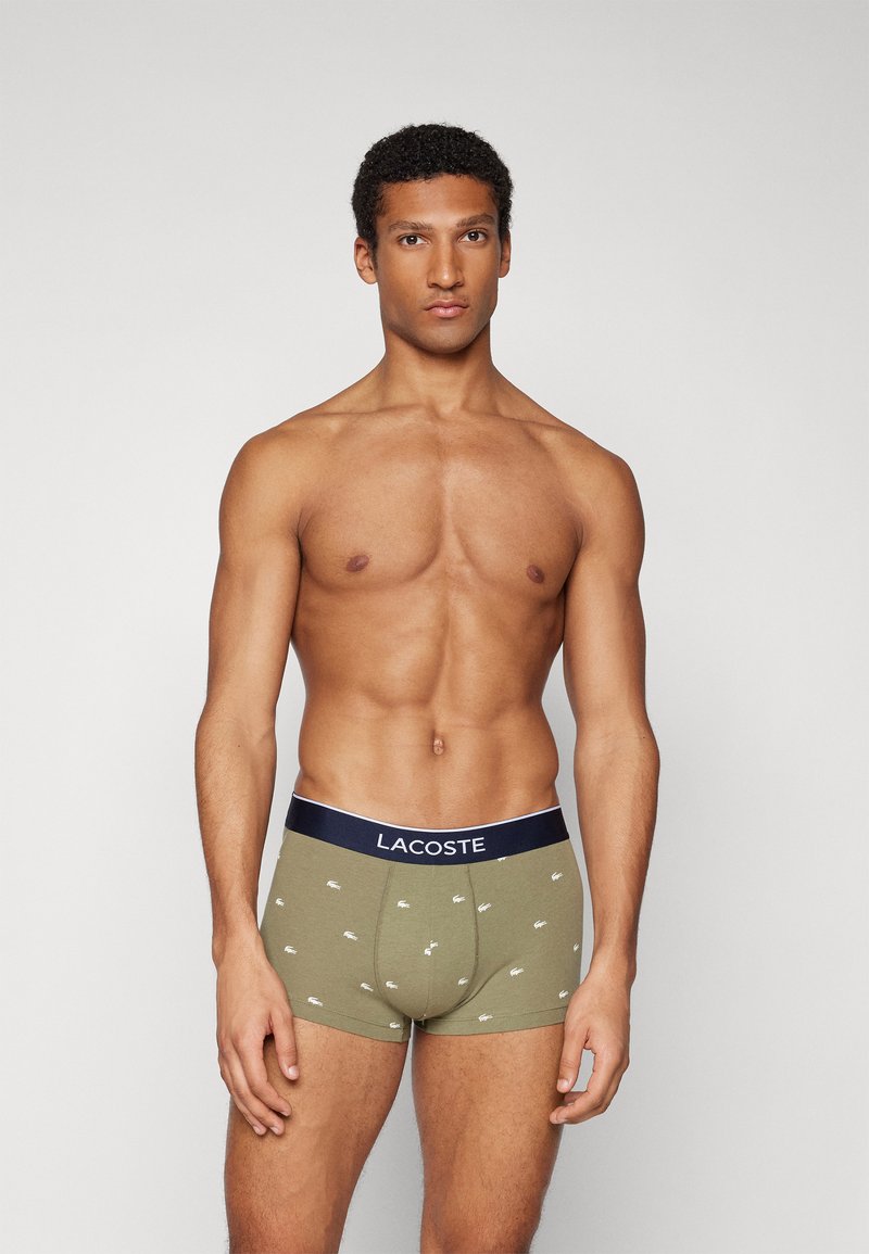 Khaki színű pamut boxer alsónadrág, sötétkék derékkal, amelyen a Lacoste logó és kis fehér krokodil minták találhatók.