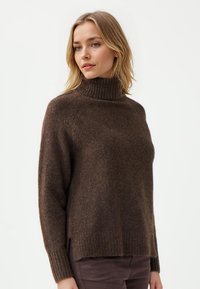 Bruine coltrui gemaakt van textuurgebreide stof, met een ontspannen pasvorm, ribbelzoom en zijsplitten voor comfort en stijl.