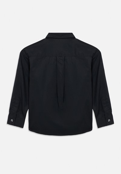 Musta pitkähiha paita, jossa on napilliset kalvosimet, taustakappale ja keskellä oleva laatikkopleenari, esitettynä tasaisena valkoisella taustalla selin.