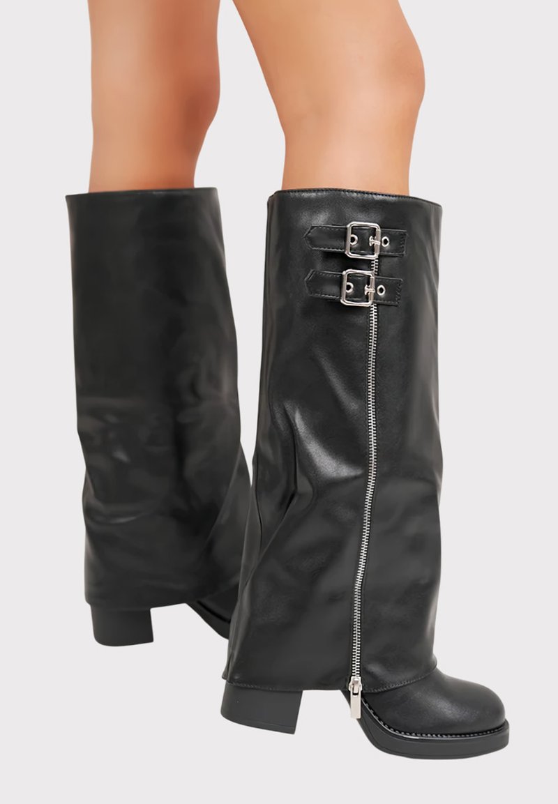 Bottes noires en simili cuir, arrivant au genou, avec une fermeture éclair, deux boucles décoratives, des talons larges et une texture lisse.