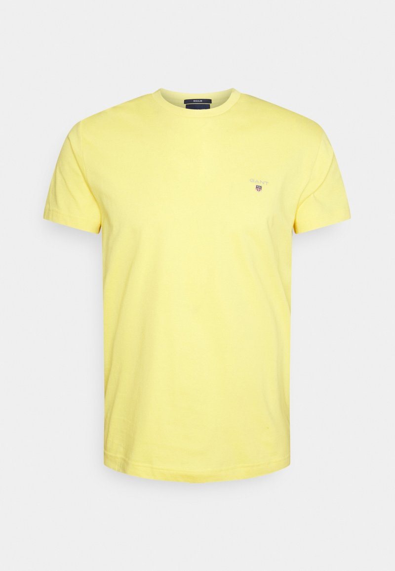 T-shirt en coton jaune avec un col rond, des manches courtes et un petit logo sur le côté gauche de la poitrine. Texture douce et coupe régulière.
