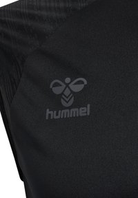 Maglietta sportiva nera con tessuto testurizzato, area liscia e logo "hummel" grigio stampato sul davanti.