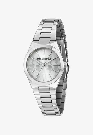 Montre en métal argenté avec un boîtier hexagonal et un cadran gris clair texturé. Caractérisée par des index allongés argentés et un bracelet à maillons.