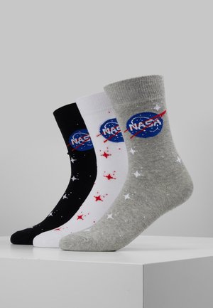 Kolme paria matkala.setterin sukka mustana, valkoisena ja harmaana. Jokaisessa on NASA-logo ja tähtikuvioita punaisena ja valkoisena. Puuvillasekoitemateriaali.