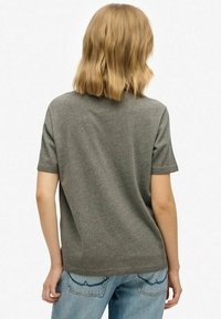 Camiseta gris de manga corta, hecha de un tejido suave, con un sencillo cuello redondo y un corte relajado, mostrada desde la parte trasera.