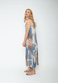 Langes, ärmelloses Kleid in Beige mit blauen und braunen Blumenmustern. Der Saum hat ein Leo-Print. Leichter Stoff.