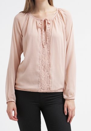 Light pink blouse with long sleeves, soft pleating, tie neckline, and floral lace detail down the center. Lightweight, flowing fabric.