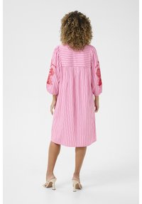 Vaaleanpunainen raidallinen mekko, jossa on punaiset kukkakirjonnat, puffettihihat ja löysä malli, joka ulottuu polven yläpuolelle. Sileä kankaan rakenne.
