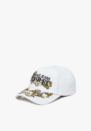 Cappellino da baseball in cotone bianco con ornate fantasie ricamate in oro e nero, con il testo "Versace Jeans Couture" sulla parte anteriore.
