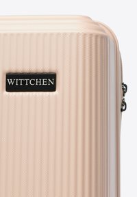 Hellrosa strukturierter Hartschalenkoffer mit schwarzem rechteckigem Wittchen-Logo und sichtbarem Reißverschluss-Zipper auf der rechten Seite.