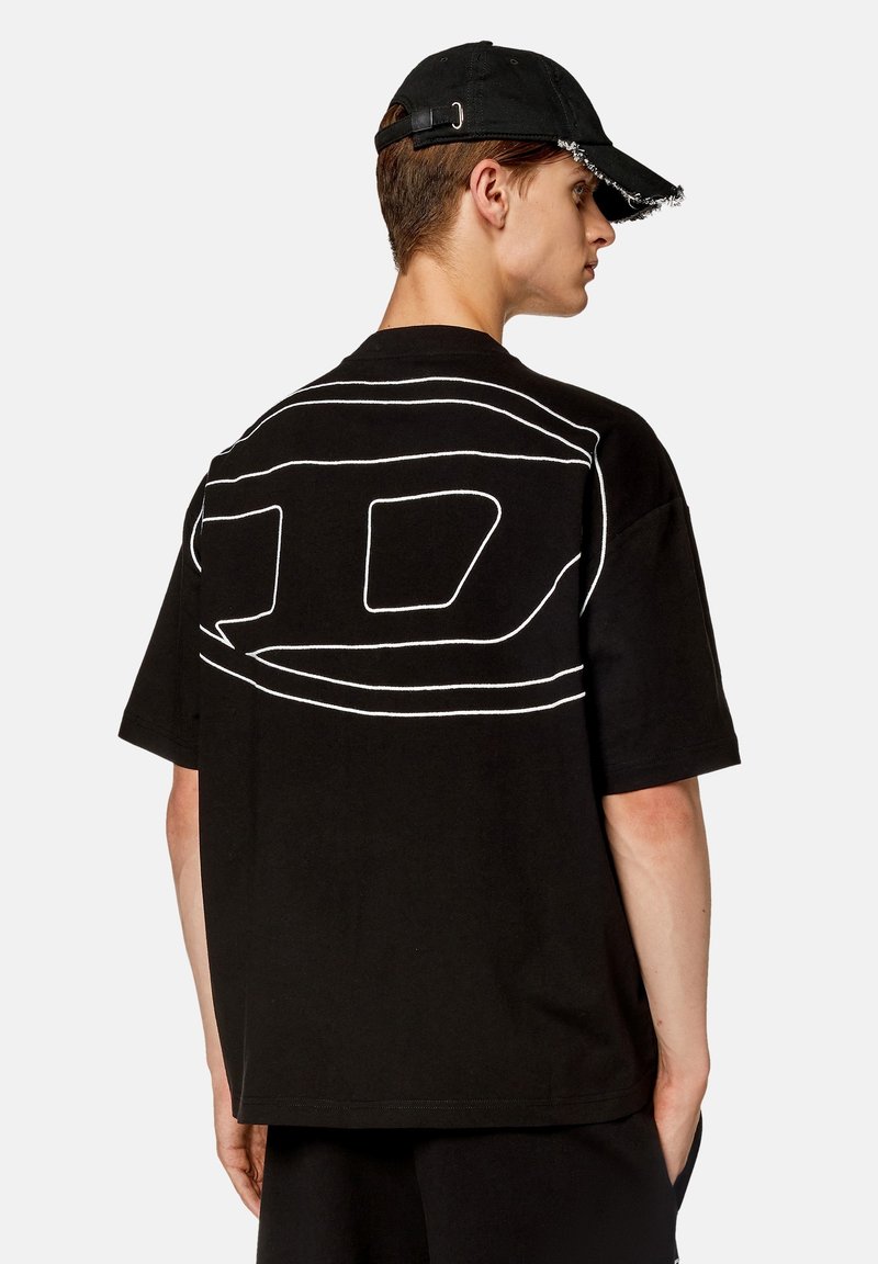 T-shirt nera oversize con un design astratto bianco sul retro. Realizzata in cotone, presenta maniche corte e scollo rotondo.