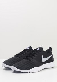 Czarne sportowe sneakersy z cholewką z siateczki, białą podeszwą oraz srebrnym, odblaskowym logo Nike w kształcie znaku Swoosh. Posiadają sznurowanie i wyściełany kołnierz.