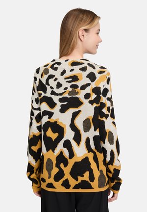 Leopardmönstrad tröja med en blandning av beige, svart och senapsgula färger, avslappnad siluett och långa ärmar, stickad textur.