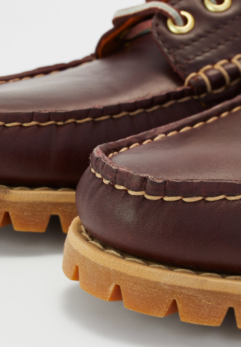 Scarpe in pelle marrone con punta arrotondata, cuciture chiare a contrasto e suola in gomma testurizzata con profonde scanalature per una migliore trazione.