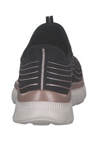 Scarpa sportiva nera con tomaia in maglia testurizzata, accenti metallici e suola in gomma. Il retro presenta un'etichetta per facilitare l'indossamento.